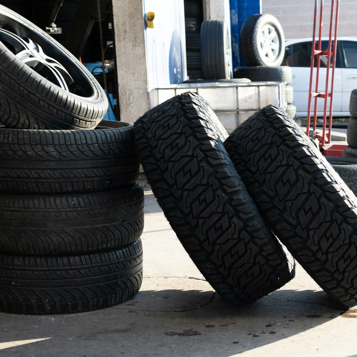 All-terrain tires and wheels staged outside a garage